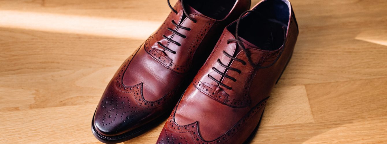 Red leather shoes stand on the light wooden floor