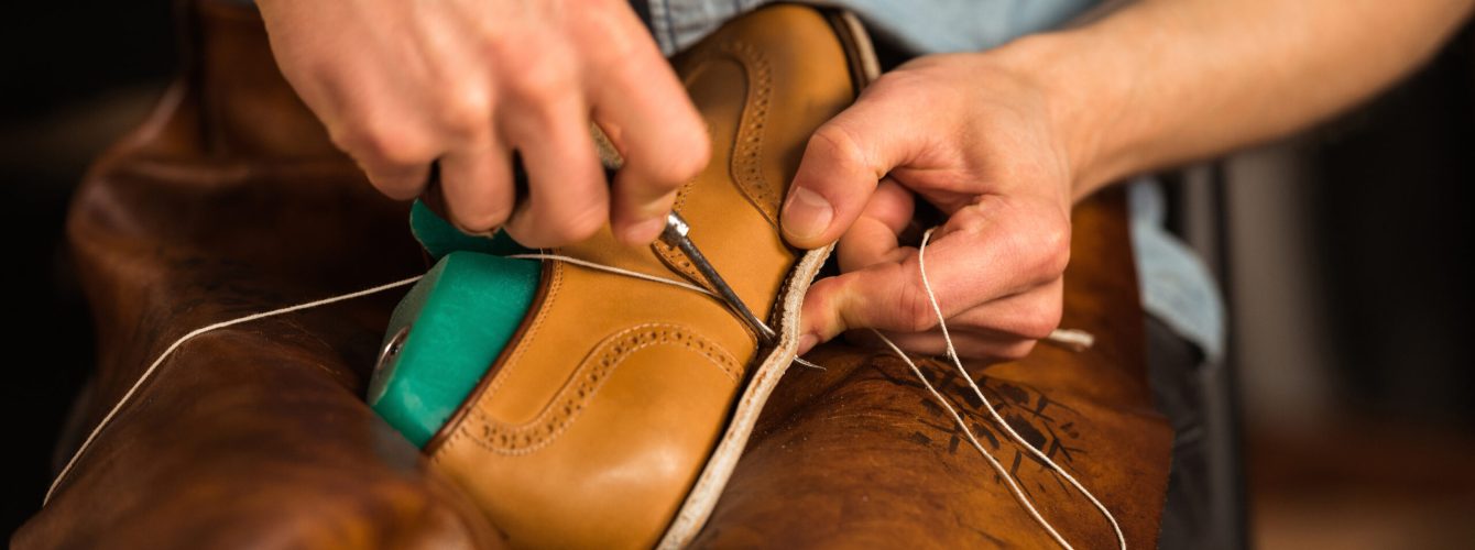 Cropped image of young shoemaker in workshop making shoes.